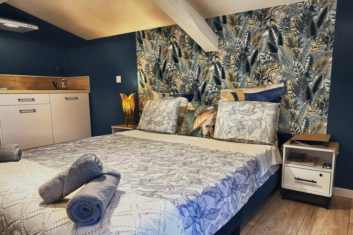 Lou Pitchoun's renovated bedroom, double bed and tropical wallpaper